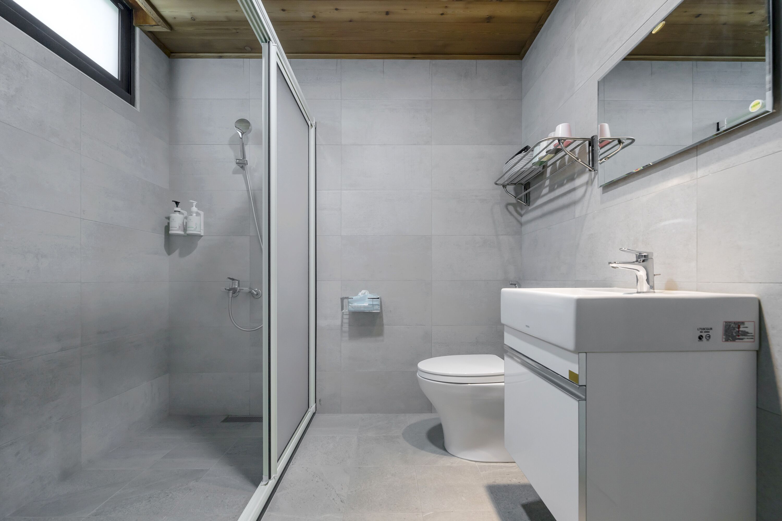 A modern bathroom with a glass shower enclosure, a toilet, and a sink with a mirror above it.