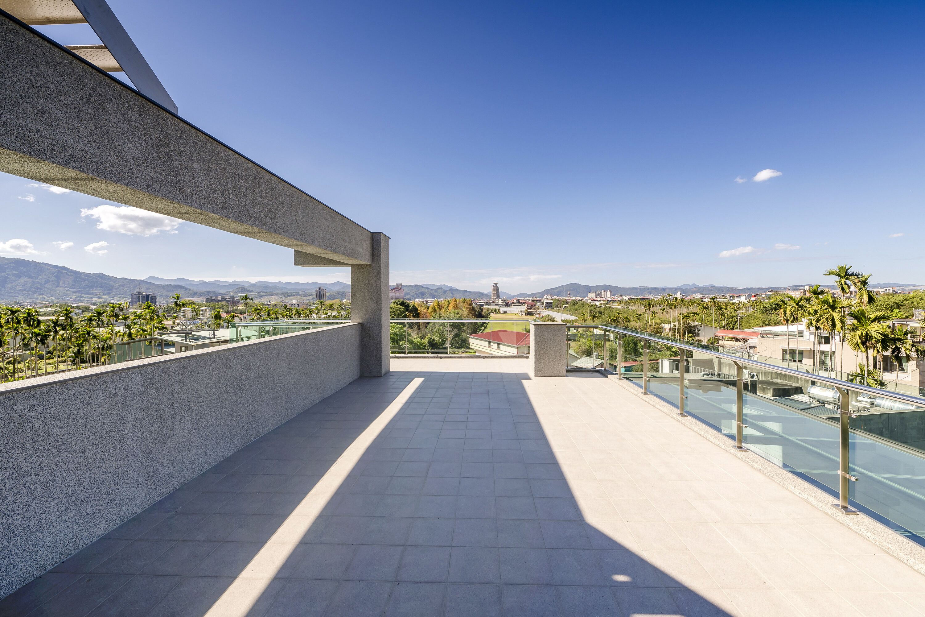 A spacious balcony with a clear view of a cityscape, including mountains and palm trees.