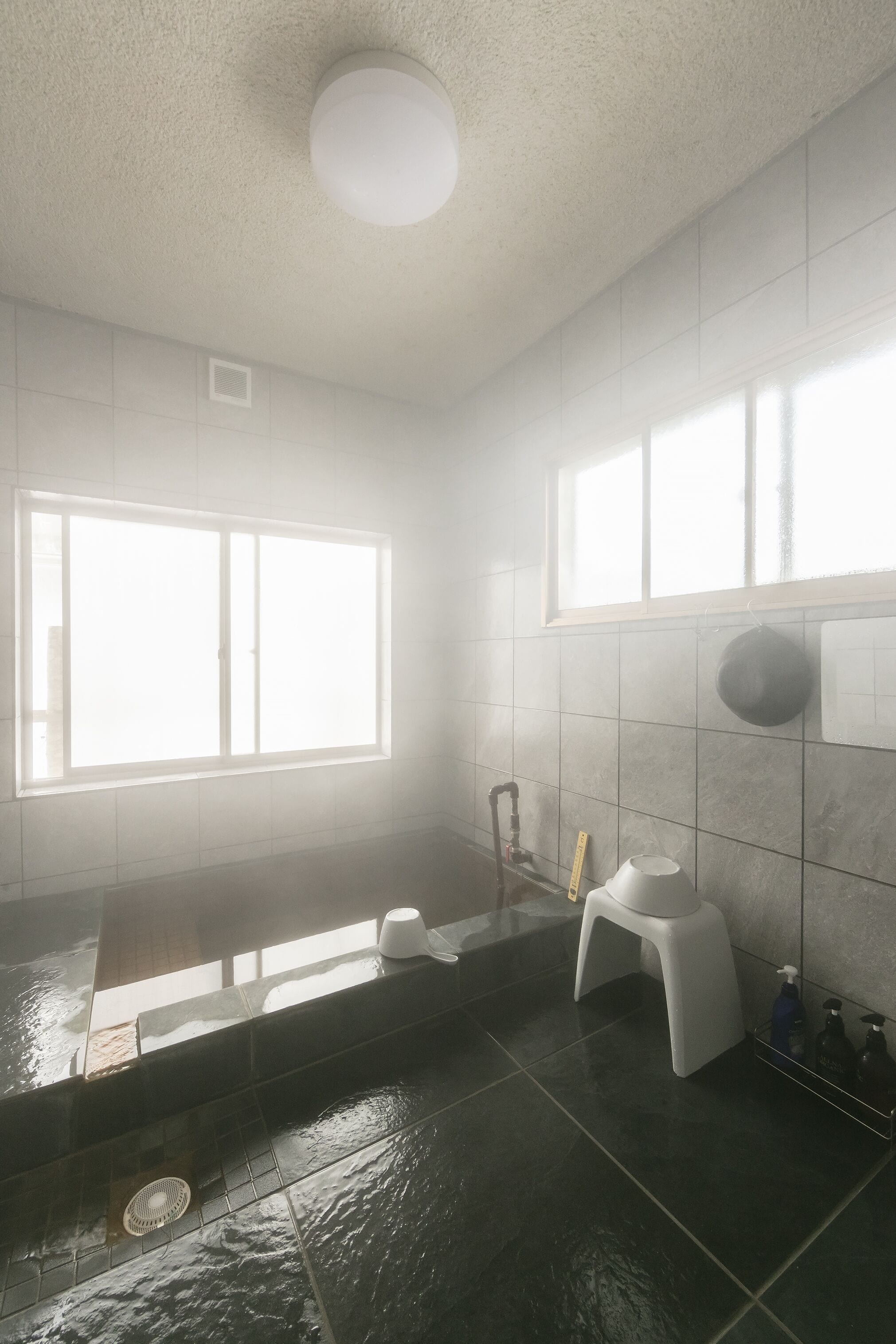 A bathroom with a bathtub, a window, a toilet, and a shower.