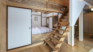Una stanza tradizionale in stile giapponese, con pavimento in tatami, una scala in legno e una porta scorrevole.