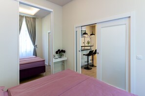 A bedroom with a bed, a desk, and a chair. There is a bathroom visible through an open door. - Bonne Chance Apartments (Zagreb)