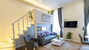 A modern living room with a staircase, a sofa, a coffee table, and a TV. - Bonne Chance Apartments (Zagreb)