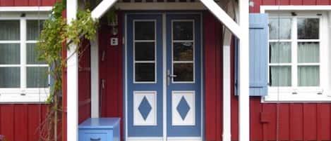 A red building with a blue door and a small porch.
