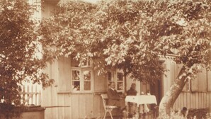 Ein altes Foto von einem Haus mit Veranda, Tisch und Stühlen.