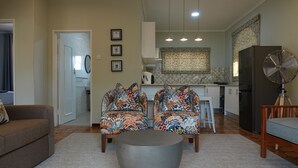 A living room with a sofa, two patterned armchairs, a coffee table, and a fan. - Zimbara (Victoria Falls)