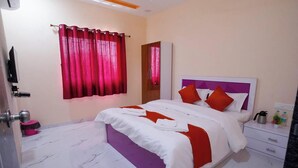 A hotel room with a bed, a nightstand, a mirror, a window with curtains, and a door. - The Serenity Resort (Mahabaleshwar)