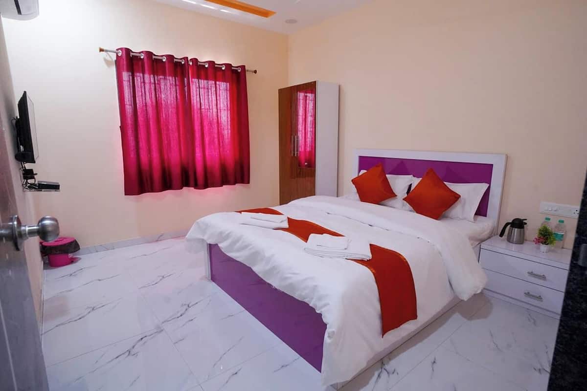A hotel room with a bed, a nightstand, a mirror, a window with curtains, and a door.