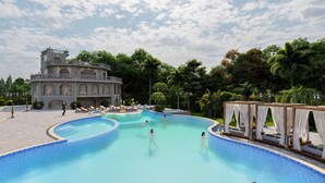 A large pool with a grand building in the background, surrounded by lush greenery. - Pokhara Panorama Resort and Spa-Luxury Redefined (Pokhara)