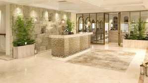 A reception area with a stone wall, a reception desk, and a seating area with chairs and a table. - Pokhara Panorama Resort and Spa-Luxury Redefined (Pokhara)