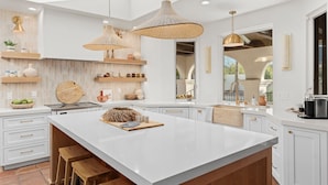 A modern kitchen with a large island, pendant lights, and a view of the outdoors. - Las Palmas  | Minutes to TPC | Tranquil Hacienda (Scottsdale)