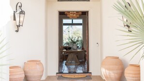 A doorway with a woven mat, a table with chairs, and potted plants. - Las Palmas  | Minutes to TPC | Tranquil Hacienda (Scottsdale)