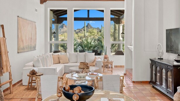 A spacious living room with a large window, a sofa set, a coffee table, and a cabinet. - Las Palmas  | Minutes to TPC | Tranquil Hacienda (Scottsdale)