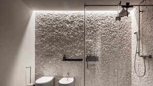 A modern bathroom with a marble wall, a glass-enclosed shower, and a bidet. - Moon suite (Pescantina)
