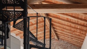 A spiral staircase with black railings, a stone fireplace, and a wooden ceiling. - Moon suite (Pescantina)