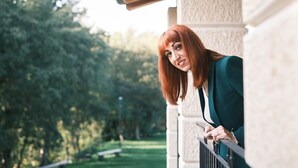 A person leaning on a balcony railing with a view of a park and trees. - Moon suite (Pescantina)