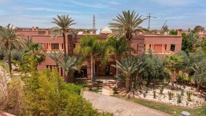 A courtyard with palm trees and a building with a flat roof. - Villa Hana B (Marrakech)