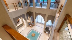 A spacious atrium with a central fountain, multiple seating areas, and a view of the outdoor balcony. - Villa Hana B (Marrakech)