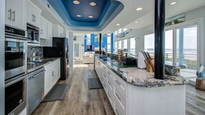 A modern kitchen with white cabinets, granite countertops, and a black refrigerator. - Beachfront 4BR/4.5BA Luxury Getaway! (Galveston)