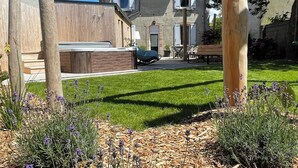 A two-story house with a well-maintained lawn and a wooden deck. - Maison des Années 30 Avec spa (Plounéour-Brignogan-plages)