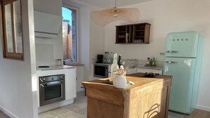 A modern kitchen with a wooden island, built-in oven, and a light blue refrigerator. - Maison des Années 30 Avec spa (Plounéour-Brignogan-plages)