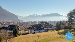 A residential area with houses on a hillside, a clear sky, and mountains in the background. - Le Sainte Anne- appartement avec vue Lac. (Annecy-le-Vieux)