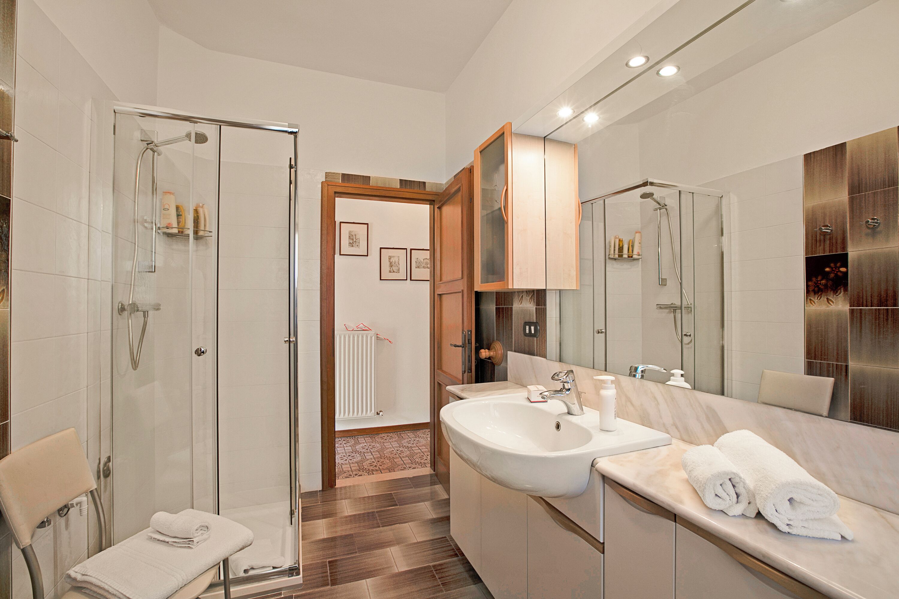 A modern bathroom with a glass-enclosed shower, a double sink vanity, and a large mirror.