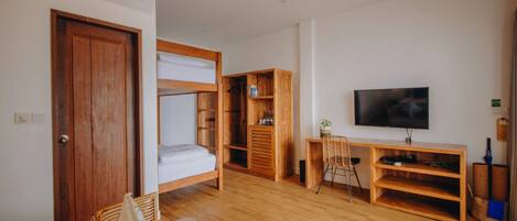 Una habitació amb llit, escriptori, televisió i una estanteria.