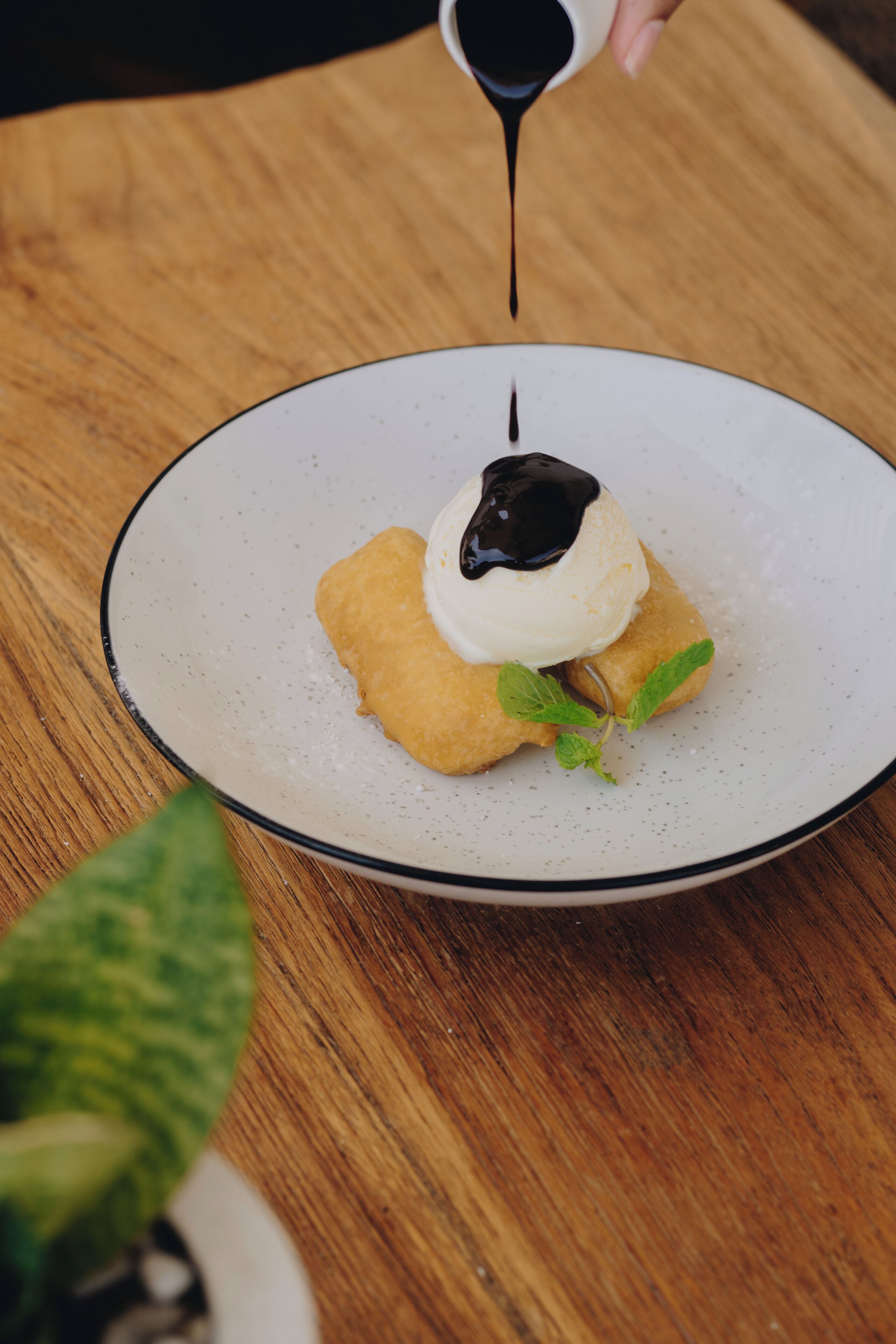 A dessert on a plate with a sauce being poured over it.