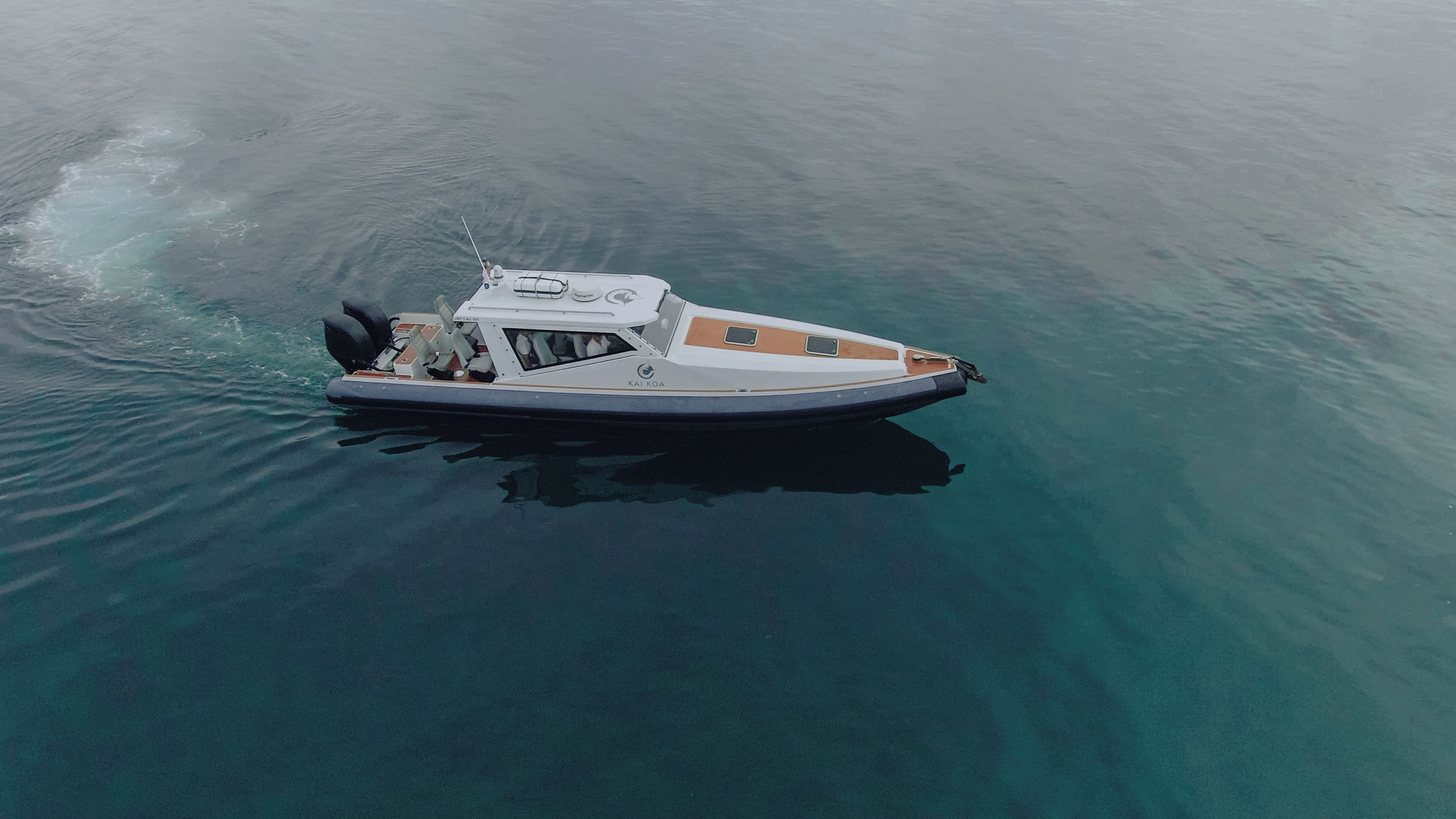 A small motorboat with a cabin and outboard motor, floating on calm water.