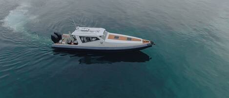 A small motorboat with a cabin and outboard motor, floating on calm water.