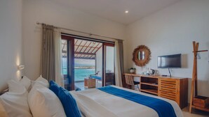 Habitación de hotel con cama, escritorio, televisor y vista al mar.