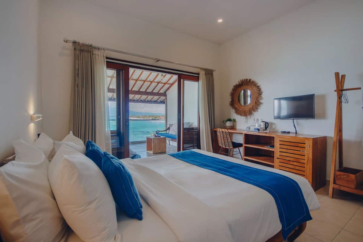 Habitació d'hotel amb llit, escriptori, televisió i vista al mar.