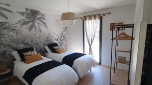 Une chambre avec deux lits, un luminaire suspendu, une armoire et une fresque murale.