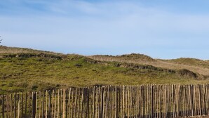 Une colline verdoyante avec une clôture en bois au premier plan.