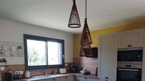 Une cuisine moderne avec une table de salle à manger ronde, des chaises noires et un luminaire suspendu.