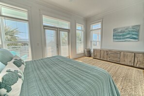 A bedroom with a bed, a window with blinds, a wall-mounted cabinet, and a painting.