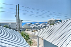 A row of buildings with corrugated metal roofs, utility poles, and a clear blue sky.