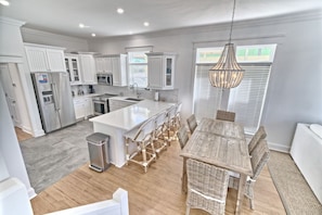 A spacious kitchen with white cabinetry, a central island, and a dining area with wicker chairs.