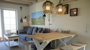 Un rincón acogedor con una mesa de madera, bancos, un sofá y un cuadro en la pared.