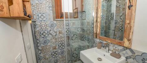 A bathroom with a shower, a sink, and a mirror.