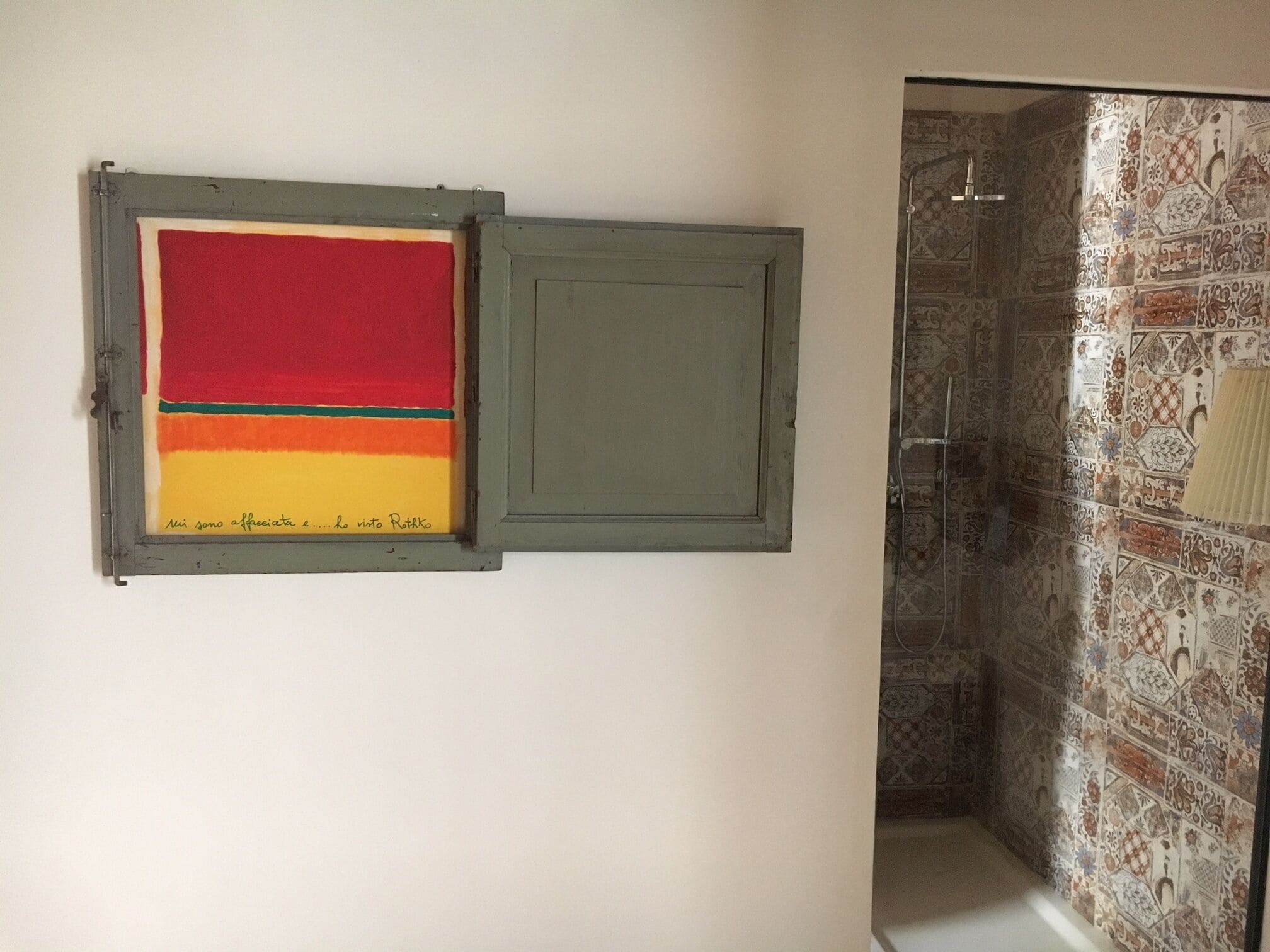 A bathroom with a shower, a wall-mounted sink, and a framed artwork.