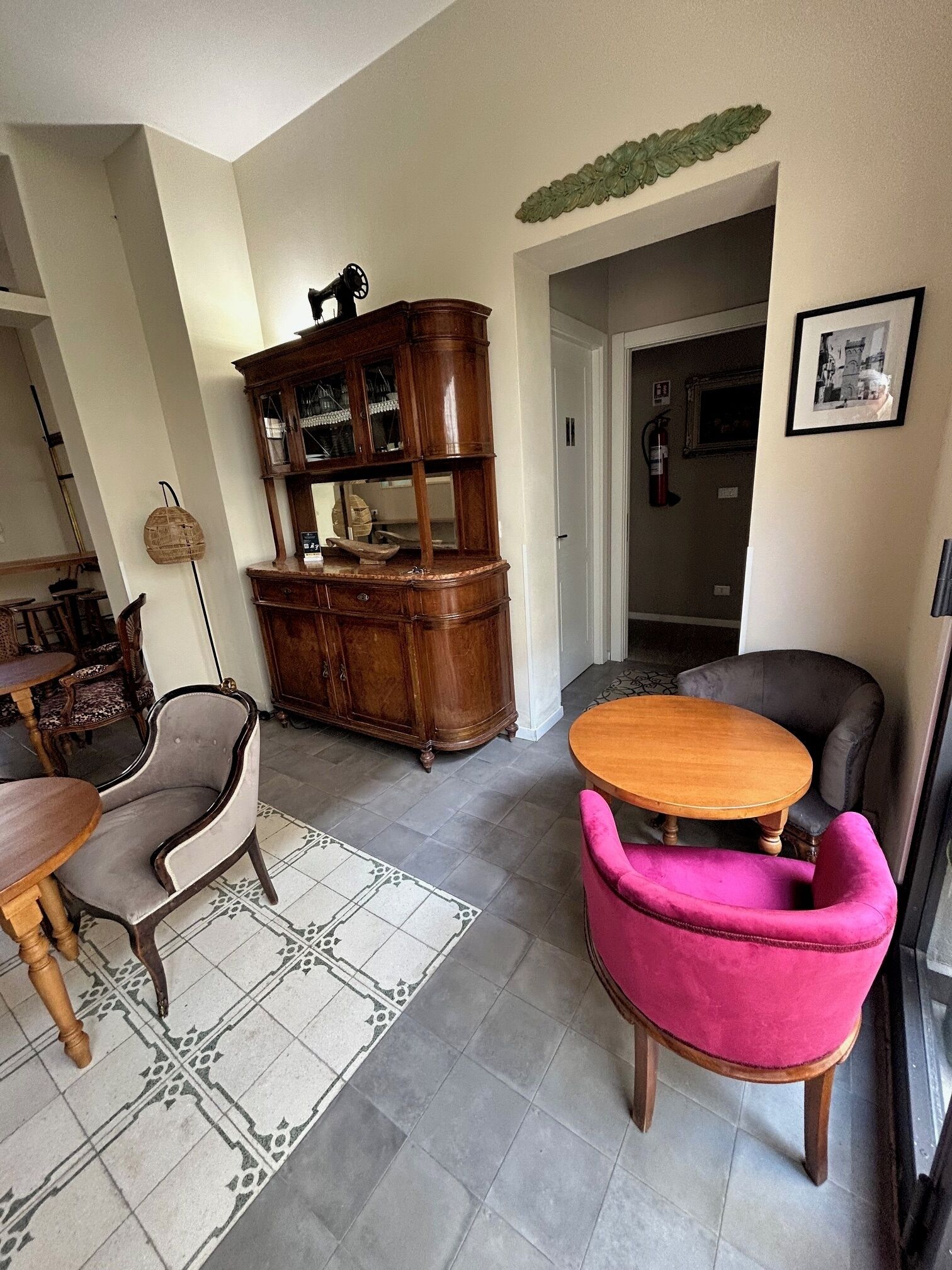 A living room with a wooden cabinet, a round wooden table, a pink armchair, and a grey armchair.