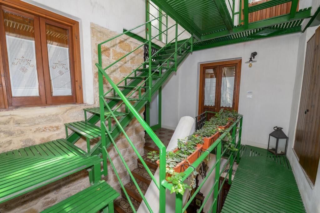 A staircase with green railings, a wooden bench, and a table with potted plants.