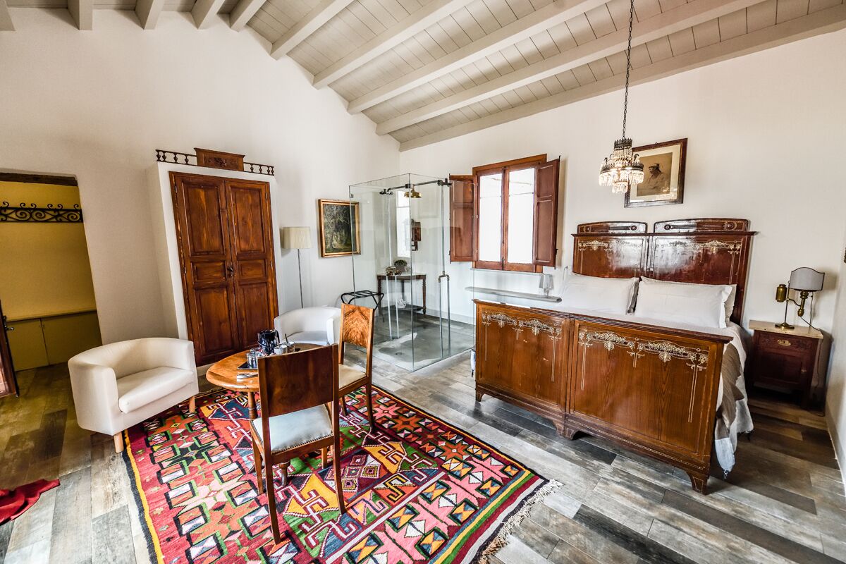 A spacious room with a large wooden cabinet, a white sofa, a colorful rug, and a glass shower enclosure.