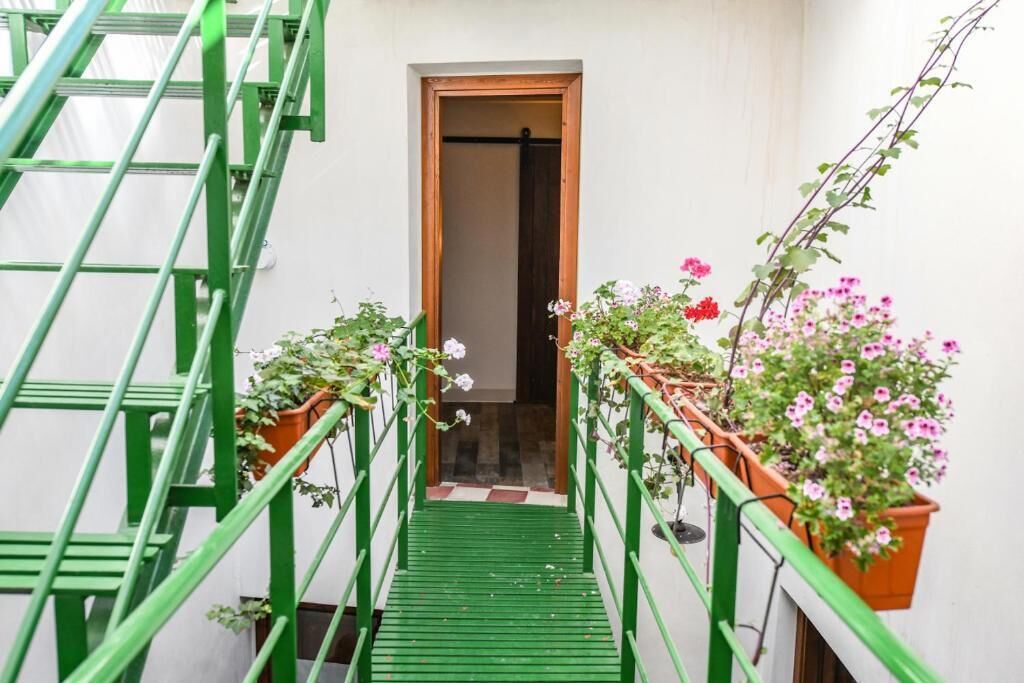 A narrow staircase with green railings leading to a doorway.