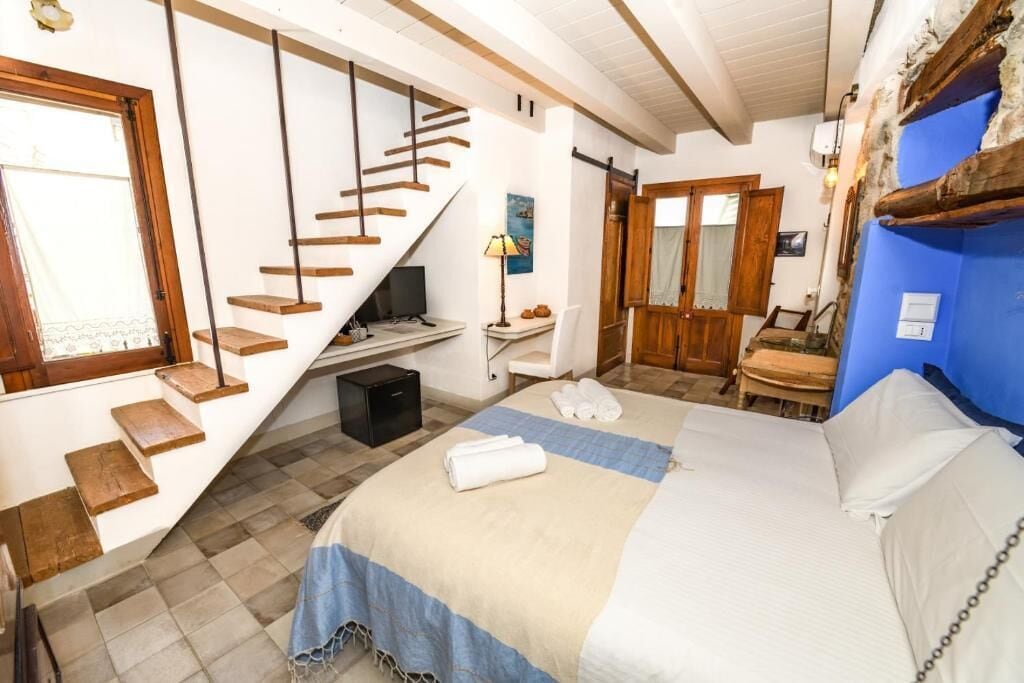A bedroom with a bed, a desk, a chair, a mirror, a wardrobe, and a staircase.