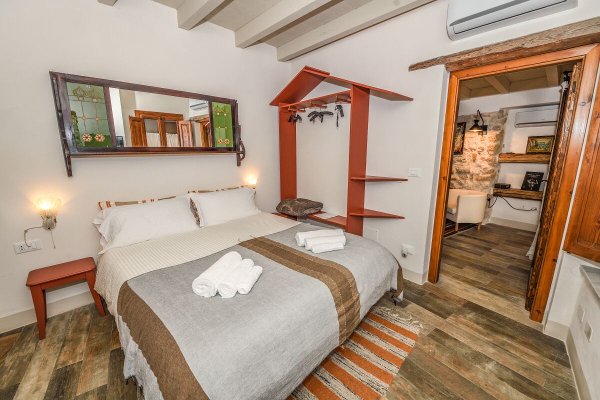 Une chambre à coucher avec un lit, un banc, un miroir et une étagère rouge.