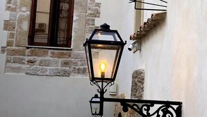 Un edificio de piedra con una ventana y un farol en la pared.
