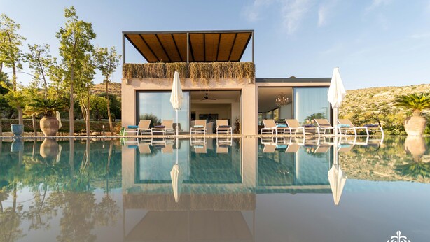 A modern villa with a pool, outdoor seating, and a view of the surrounding landscape. - Villa Dama - Luxury Escape (Avola)
