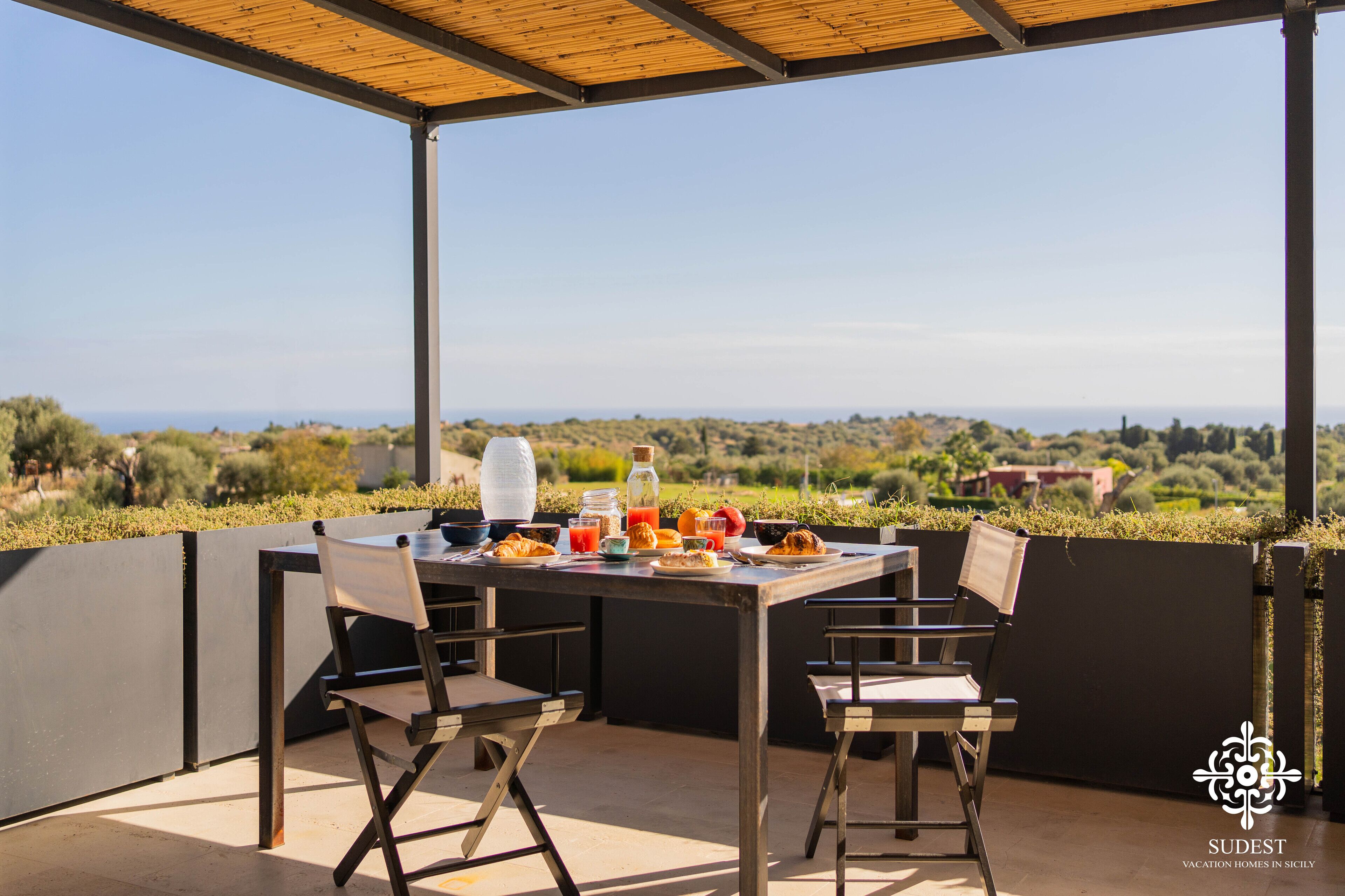 An outdoor dining area with a table set for two, overlooking a scenic landscape.